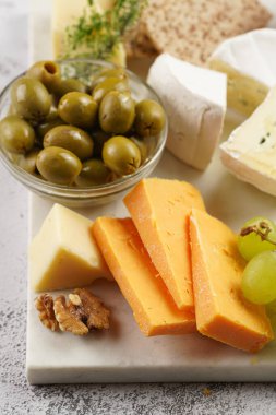 Cheese platter with organic cheeses - blue cheese cheddar, emmantaler, french soft cheese with strong smell, italian parmesan, grapes, tomatoes, olives, nuts and crackers on marble board