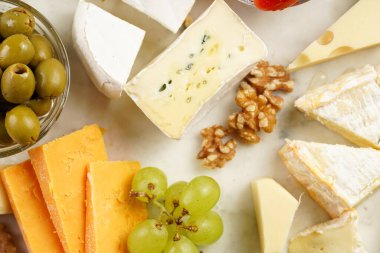 Organik peynirli peynir tabağı - mavi peynirli çedar, emmantaler, güçlü kokulu Fransız yumuşak peyniri, İtalyan parmesan peyniri, üzümler, domates, zeytin, fındık ve mermer tahtada kraker
