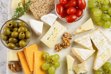 Organik peynirli peynir tabağı - mavi peynirli çedar, emmantaler, güçlü kokulu Fransız yumuşak peyniri, İtalyan parmesan peyniri, üzümler, domates, zeytin, fındık ve mermer tahtada kraker