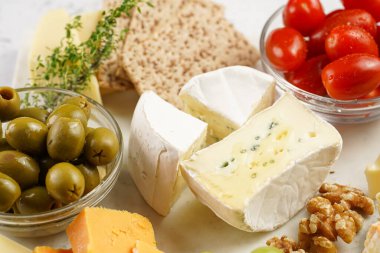 Organik peynirli peynir tabağı - mavi peynirli çedar, emmantaler, güçlü kokulu Fransız yumuşak peyniri, İtalyan parmesan peyniri, üzümler, domates, zeytin, fındık ve mermer tahtada kraker