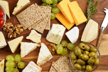Organik peynirli peynir tabağı - mavi peynirli çedar, emmantaler, güçlü kokulu Fransız yumuşak peyniri, İtalyan parmesan peyniri, üzümler, domates, zeytin, fındık ve tahta üzerinde krakerler