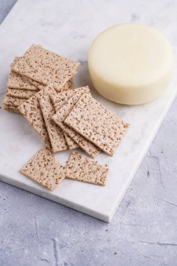 Sağlıklı çıtır çıtır krakerler susam tohumlu ve mermer tahtada yuvarlak peynirli kaş kaval.