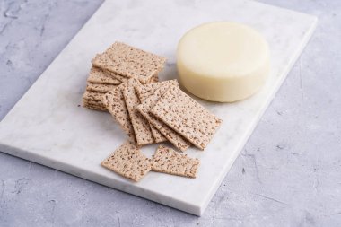 Sağlıklı çıtır çıtır krakerler susam tohumlu ve mermer tahtada yuvarlak peynirli kaş kaval.