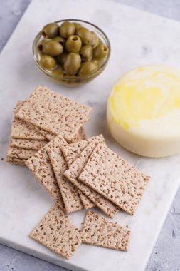 Sağlıklı çıtır çıtır krakerler susam tohumlu, yeşil zeytinli ve mermer tahtada yuvarlak peynirli kaş kaval.