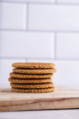 Stroopwafel - geleneksel Hollanda usulü karamelli gözleme - tahta bir tahtanın üzerinde üst üste istiflenmiş, beyaz mutfak