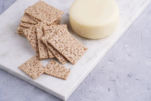 Sağlıklı çıtır çıtır krakerler susam tohumlu ve mermer tahtada yuvarlak peynirli kaş kaval.