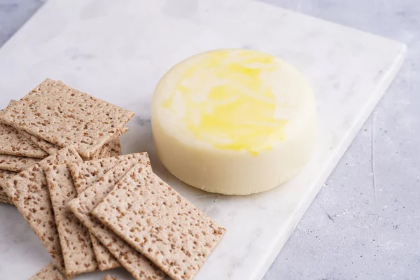 Sağlıklı çıtır çıtır krakerler susam tohumlu ve mermer tahtada yuvarlak peynirli kaş kaval.