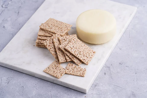 Sağlıklı çıtır çıtır krakerler susam tohumlu ve mermer tahtada yuvarlak peynirli kaş kaval.