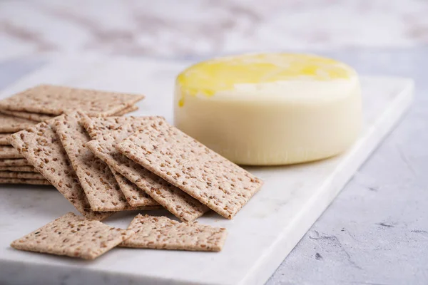 Sağlıklı çıtır çıtır krakerler susam tohumlu ve mermer tahtada yuvarlak peynirli kaş kaval.