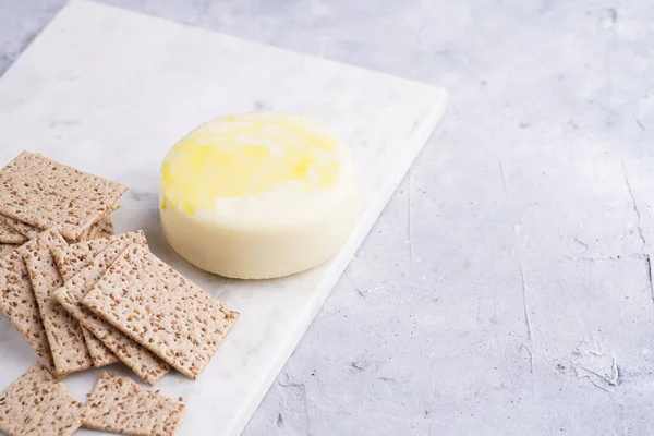 Sağlıklı çıtır çıtır krakerler susam tohumlu ve mermer tahtada yuvarlak peynirli kaş kaval.