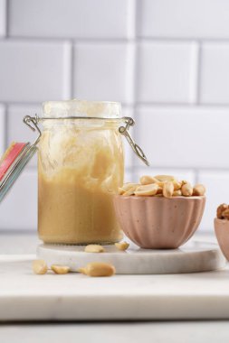 Pembe kaselerde yer fıstığı, ev yapımı fıstık ezmesi mermer tahtalarda mason kavanozunda fıstık ezmesi