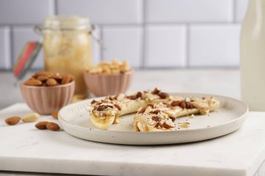 Fıstık ezmesi, kuru üzüm, badem ve beyaz tabakta chia tohumlarıyla hazır iki muz.