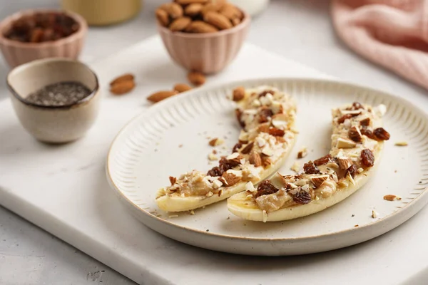 Fıstık ezmesi, kuru üzüm, badem ve beyaz tabakta chia tohumlarıyla hazır iki muz.