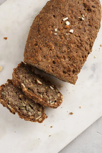 Ev yapımı glütensiz ve mayasız karabuğday ekmeği ayçiçeği, kabak tohumu ve fındıklı ekmek, beyaz mermer tahtada dilimler halinde dilimlenmiş.