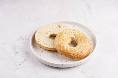 Boş bir simit mermer arka planda beyaz noktalı tabakta ikiye bölünmüş. Sandviç hazırlıyorum.