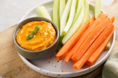 Paprika çan biberi humus sosu portakal kabağı püresi, havuç ve salatalık gibi görünüyor. Uzun şeritler ve yuvarlak bir tabakta kesilmiş çubuklar.