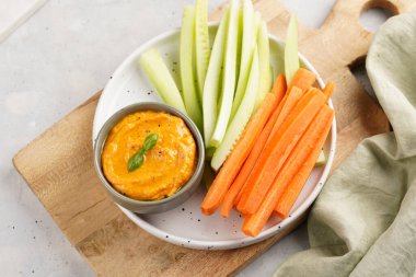 Paprika çan biberi humus sosu portakal kabağı püresi, havuç ve salatalık gibi görünüyor. Uzun şeritler ve yuvarlak bir tabakta kesilmiş çubuklar.