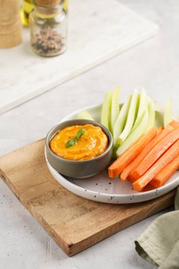 Paprika çan biberi humus sosu portakal kabağı püresi, havuç ve salatalık gibi görünüyor. Uzun şeritler ve yuvarlak bir tabakta kesilmiş çubuklar.