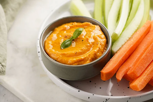 Paprika çan biberi humus sosu portakal kabağı püresi, havuç ve salatalık gibi görünüyor. Uzun şeritler ve yuvarlak bir tabakta kesilmiş çubuklar.