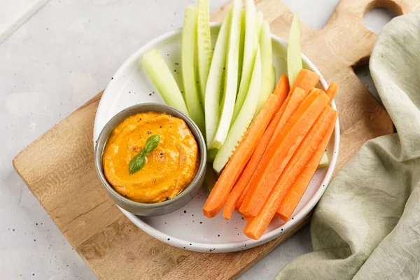 Paprika çan biberi humus sosu portakal kabağı püresi, havuç ve salatalık gibi görünüyor. Uzun şeritler ve yuvarlak bir tabakta kesilmiş çubuklar.