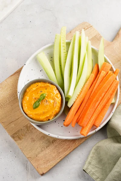 Paprika çan biberi humus sosu portakal kabağı püresi, havuç ve salatalık gibi görünüyor. Uzun şeritler ve yuvarlak bir tabakta kesilmiş çubuklar.
