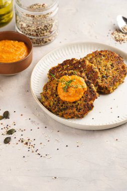 Paprika humusuyla kaplı bir tabakta havuç ve kinoa krepleri, ayçiçeği çekirdekleri. Sağlıklı vejetaryen yiyecekler - bitki temelli diyet kavramı.