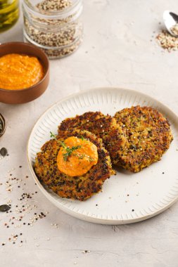 Paprika humusuyla kaplı bir tabakta havuç ve kinoa krepleri, ayçiçeği çekirdekleri. Sağlıklı vejetaryen yiyecekler - bitki temelli diyet kavramı.