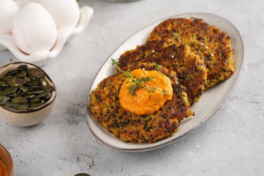 Paprika humusuyla kaplı bir tabakta havuç ve kinoa krepleri, ayçiçeği çekirdekleri. Sağlıklı vejetaryen yiyecekler - bitki temelli diyet kavramı.