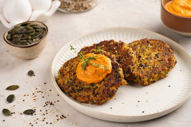 Paprika humusuyla kaplı bir tabakta havuç ve kinoa krepleri, ayçiçeği çekirdekleri. Sağlıklı vejetaryen yiyecekler - bitki temelli diyet kavramı.