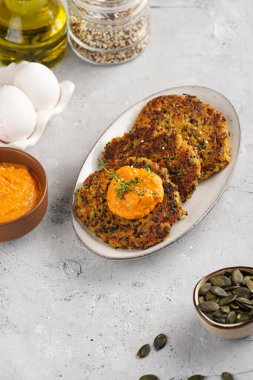 Paprika humusuyla kaplı bir tabakta havuç ve kinoa krepleri, ayçiçeği çekirdekleri. Sağlıklı vejetaryen yiyecekler - bitki temelli diyet kavramı.