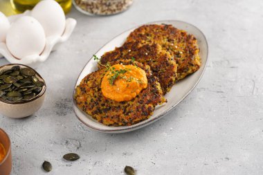 Paprika humusuyla kaplı bir tabakta havuç ve kinoa krepleri, ayçiçeği çekirdekleri. Sağlıklı vejetaryen yiyecekler - bitki temelli diyet kavramı.