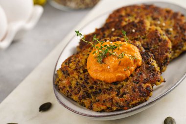 Paprika humusuyla kaplı bir tabakta havuç ve kinoa krepleri, ayçiçeği çekirdekleri. Sağlıklı vejetaryen yiyecekler - bitki temelli diyet kavramı.