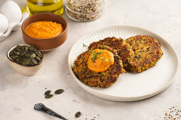 Paprika humusuyla kaplı bir tabakta havuç ve kinoa krepleri, ayçiçeği çekirdekleri. Sağlıklı vejetaryen yiyecekler - bitki temelli diyet kavramı.