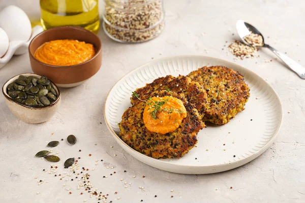 Paprika humusuyla kaplı bir tabakta havuç ve kinoa krepleri, ayçiçeği çekirdekleri. Sağlıklı vejetaryen yiyecekler - bitki temelli diyet kavramı.