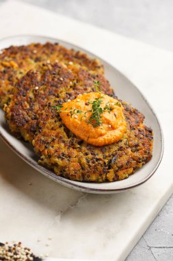 Paprika humusuyla kaplı bir tabakta havuç ve kinoa krepleri, ayçiçeği çekirdekleri. Sağlıklı vejetaryen yiyecekler - bitki temelli diyet kavramı.