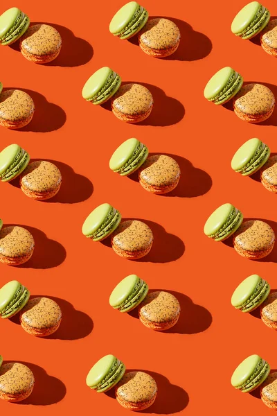 Kalıp iki turuncu ve yeşil badem kurabiyeleri kırmızı arkaplanda sert ışıkta