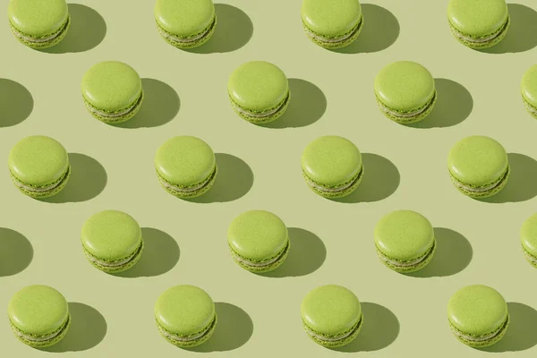 Hard light pattern of a green macaron pastry photographed on light green surface