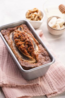 Muzlu çikolatalı ekmek, metalik kabartma kalıbında ceviz ve gri nötr arka planda yaratıcı ışıklandırmalı malzemeler.