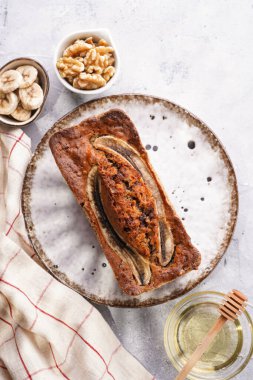 Muzlu çikolatalı ekmek, beyaz tabakta cevizli, kahverengi kenarlı ve gri, nötr arka planlı, yaratıcı ışıklandırmalı, üst manzaralı.