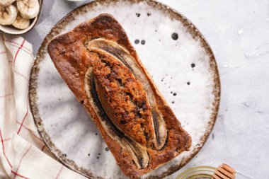 Muzlu çikolatalı ekmek, beyaz tabakta cevizli, kahverengi kenarlı ve gri, nötr arka planlı, yaratıcı ışıklandırmalı, üst manzaralı.