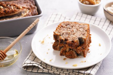 Damalı mutfak peçetesine cevizli muzlu çikolatalı ekmek dilimleri ve gri tarafsız bir arkaplanda malzemeler.