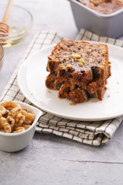 Damalı mutfak peçetesine cevizli muzlu çikolatalı ekmek dilimleri ve gri tarafsız bir arkaplanda malzemeler.