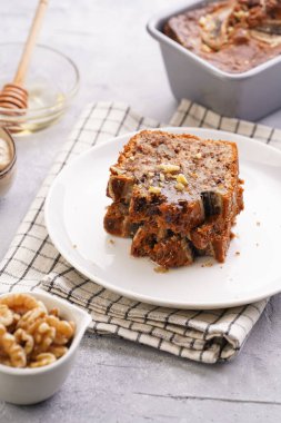 Damalı mutfak peçetesine cevizli muzlu çikolatalı ekmek dilimleri ve gri tarafsız bir arkaplanda malzemeler.