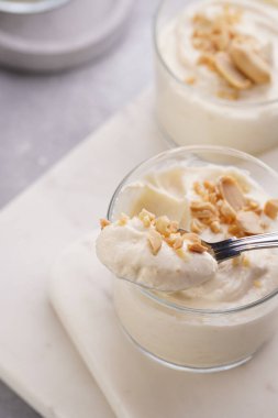 Kremalı yoğurtlu tatlı, krem peynirli ve fıstık ezmeli mermer tepside çay kaşığıyla.