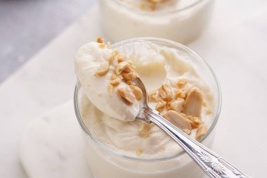 Kremalı yoğurtlu tatlı, krem peynirli ve fıstık ezmeli mermer tepside çay kaşığıyla.