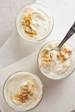 Kremalı yoğurtlu tatlı, krem peynirli ve fıstık ezmeli mermer tepside çay kaşığıyla.
