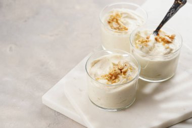 Kremalı yoğurtlu tatlı, krem peynirli ve fıstık ezmeli mermer tepside çay kaşığıyla.