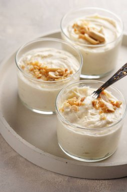 Kremalı yoğurtlu tatlı, krem peynirli ve fıstık ezmeli çay kaşığıyla beton tepside.