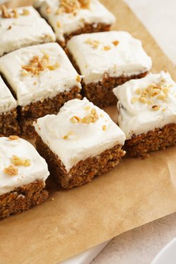 Ev yapımı havuçlu cevizli kek, topraklanmış badem ve fındıklı ve beyaz krem peynirli üst tabaka: parşömen kağıdında birkaç kesik parça