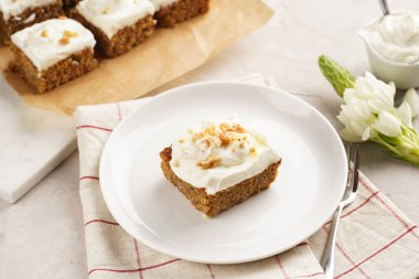 Ev yapımı havuçlu cevizli kek, topraklanmış bademler, fındıklı ve beyaz krem peynirli üst tabakta pembe peçeteli.